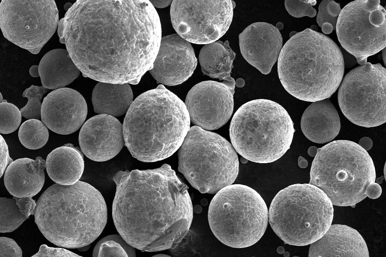 SEM image of gas atomized metal powder, with many small satellites attached to larger particles